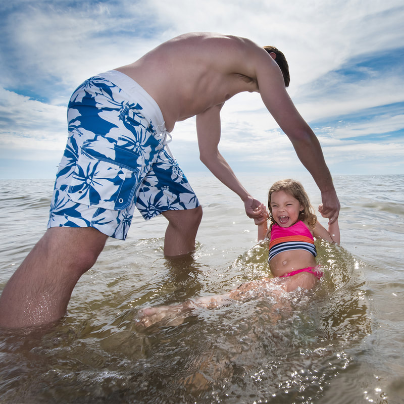 A father and daughter splashing in Lake Michigan