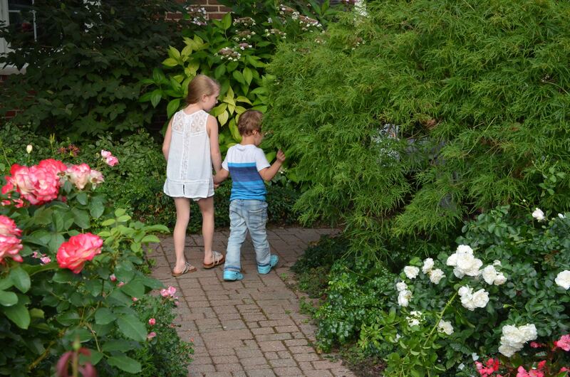 Two children walking a brick path through the Rose Garden
